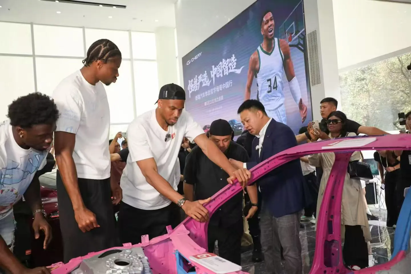 Giannis Antetokounmpo with Chery’s team, looking at a car body on display